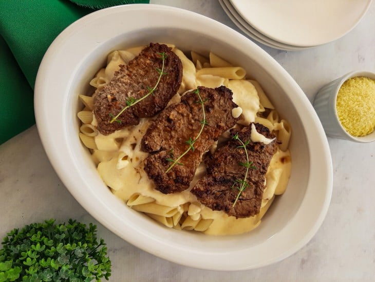 Travessa preenchida com o macarrão, o molho de 4 queijos e os medalhões de filé mignon.