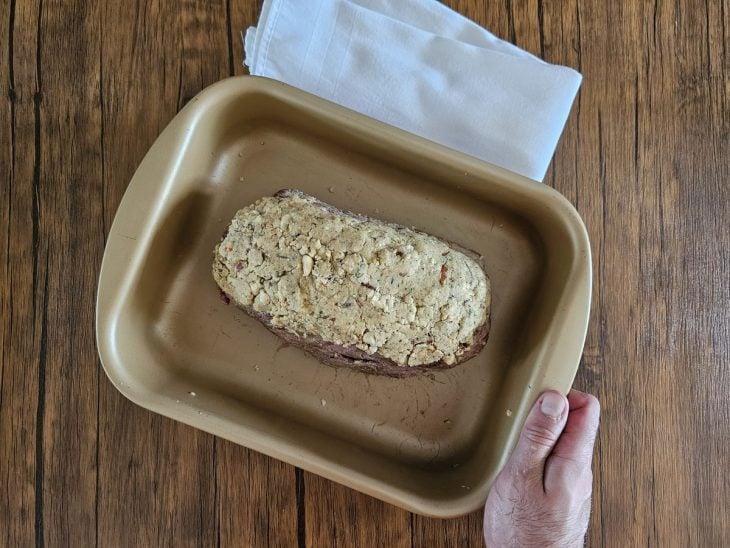 Forma com a peça de filé mignon com a farofa de castanhas disposta por cima.