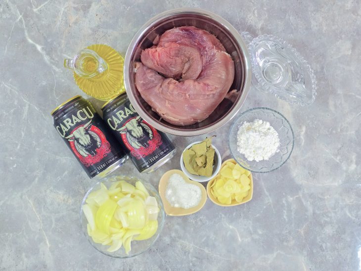Ingredientes organizados na bancada com alho picado e cebola cortada em pétalas.