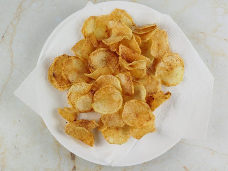 Batatas sendo fritas no mesmo óleo até ficarem douradas e crocantes.