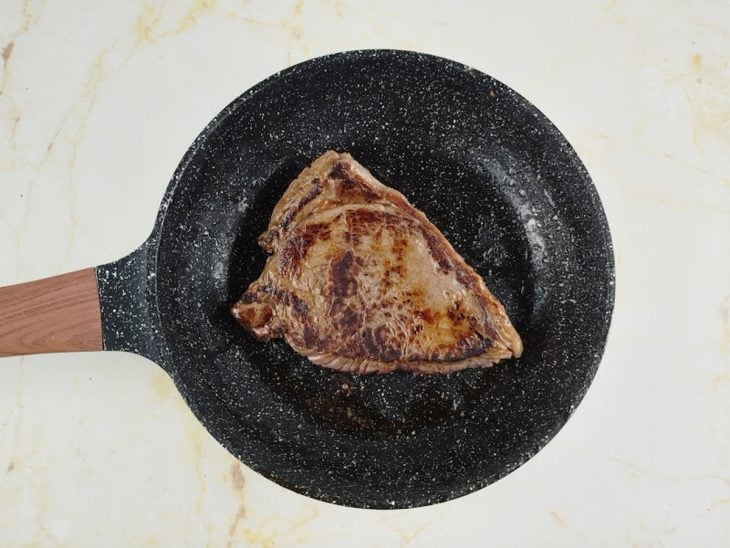 Carne sendo virada para dourar o outro lado.