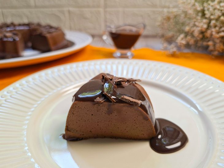 Flan coberto com calda e raspas de chocolate.