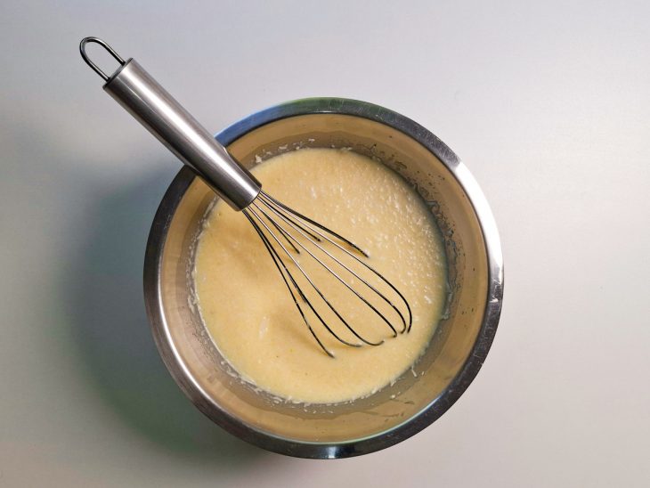 Ingredientes misturados numa tigela com auxílio de um fouet.