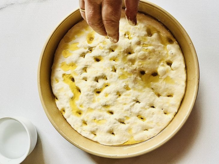 Massa de focaccia furadinha e regada com azeite.