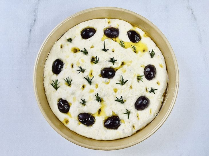 Massa de focaccia com azeitonas pretas, alecrim e azeite.