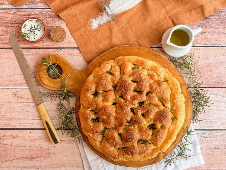 Focaccia pronta para consumo sobre uma tábua de cozinha.
