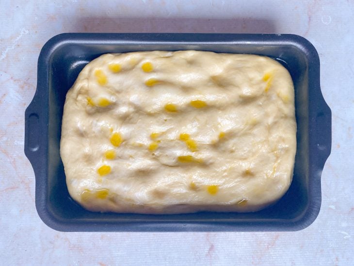Azeite espalhado sobre a massa da focaccia.