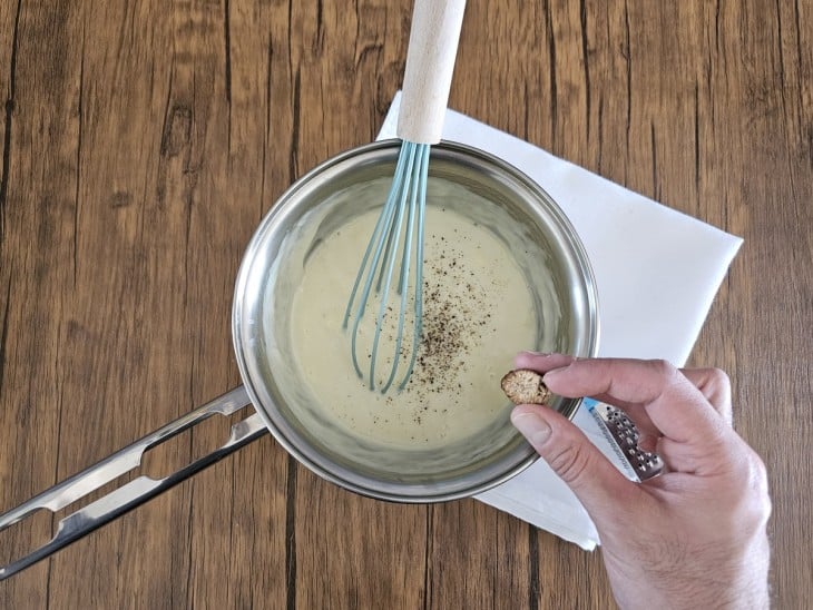 Noz-moscada sendo ralada na panela com creme de queijos.