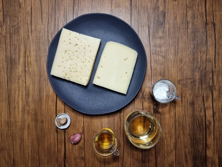 Ingredietes do fondue de queijo reunidos na bancada.