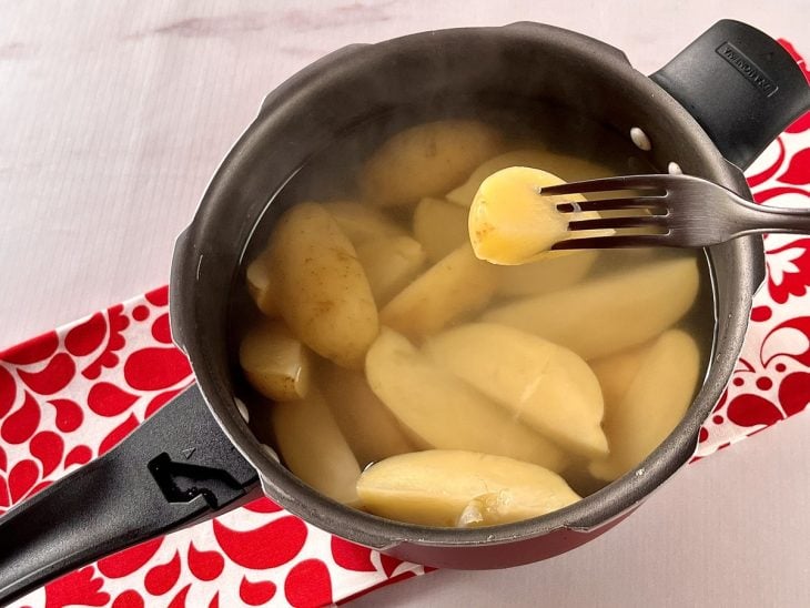 Uma panela de pressão contendo água e batatas cozidas.