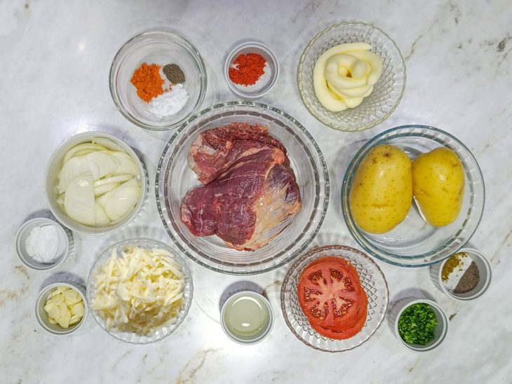 Ingredientes organizados na bancada com carne, legumes e temperos.