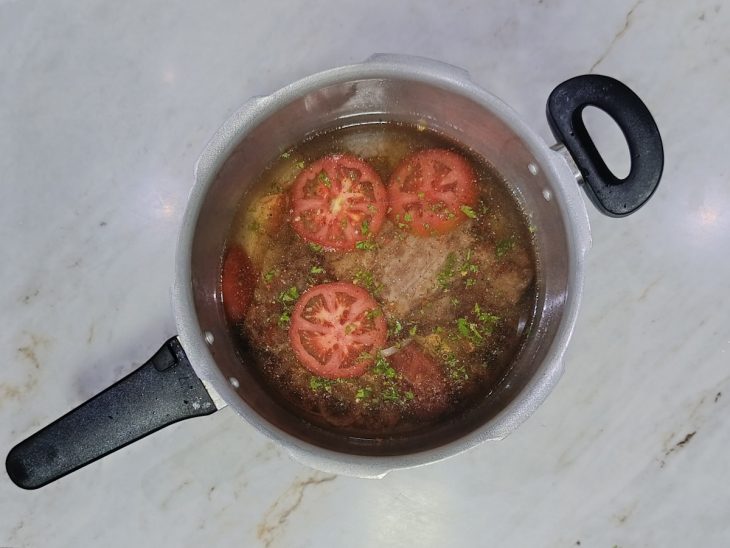 Carne cozinhando na pressão coberta com água.