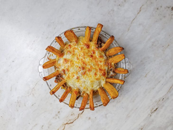 Batatas dispostas nas laterais e catupiry sobre a carne.