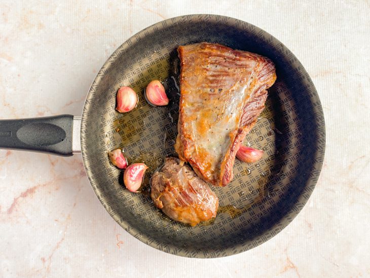 Na frigideira, a peça da fraldinha e os alhos.