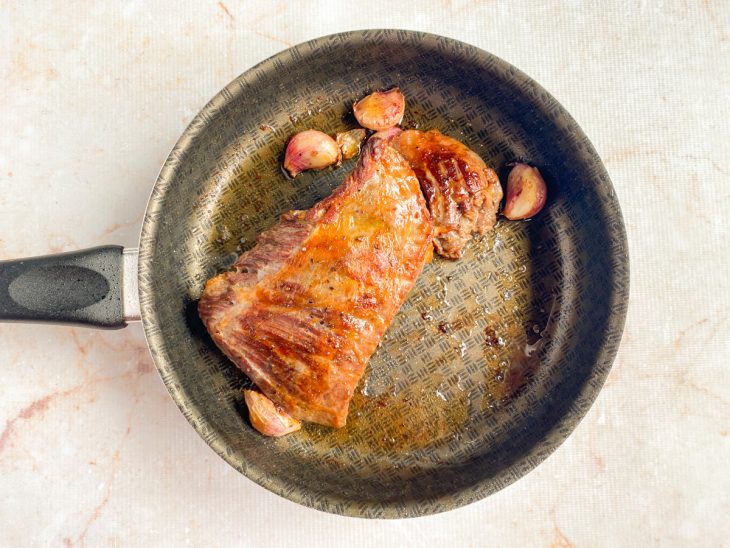Na frigideira, peça da fraldinha virada e dourada.
