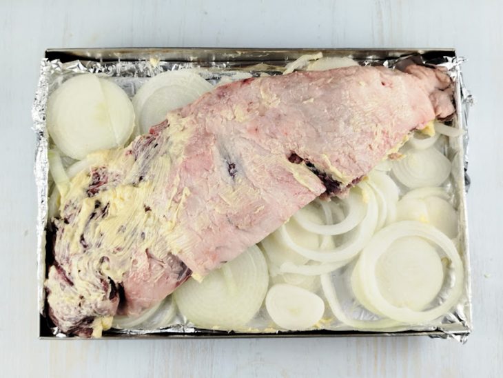 Peça de fraldinha sobre as rodelas de cebola na forma.