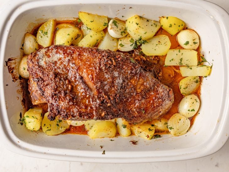 Um refratário com as cebolas, as batatas, o molho e a carne.