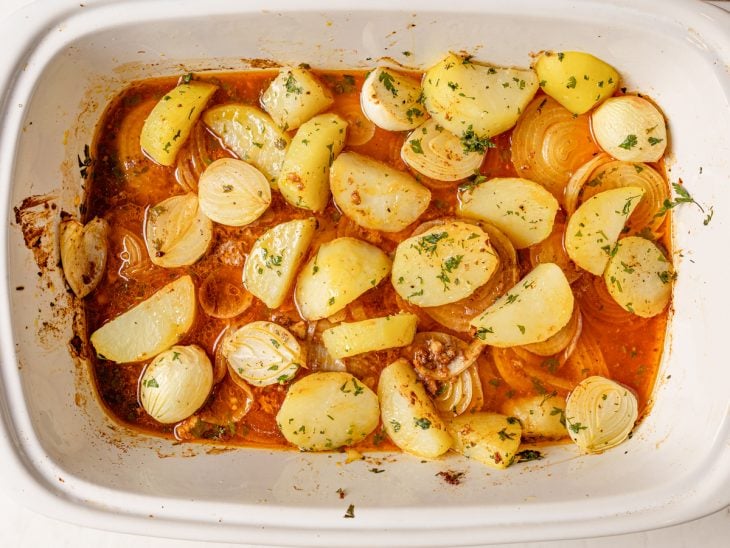 Um refratário com as cebolas, o molho e as batatas.