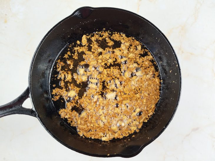 Alho dourando na manteiga em frigideira em fogo baixo.