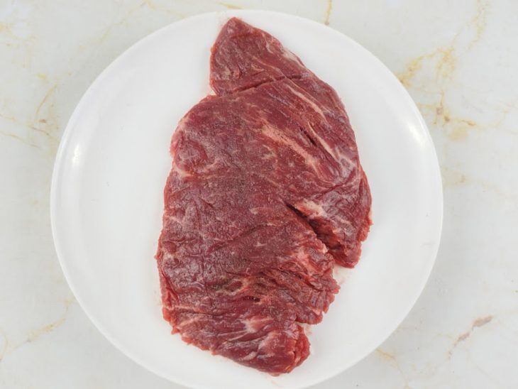 Fraldinha sendo temperada com sal e pimenta dos dois lados.