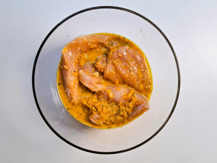 Filés de frango envolvidos por temperos na tigela.