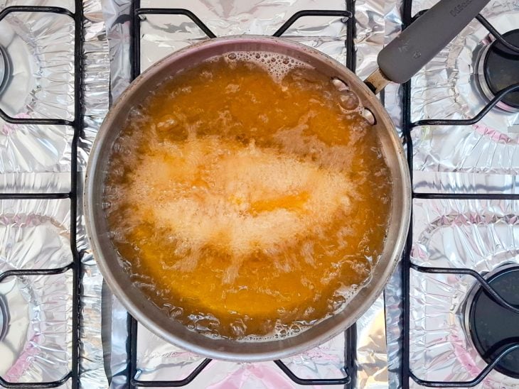 Filé de frango fritando em óleo quente na panela.