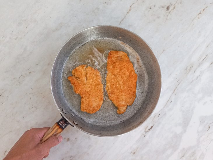 frango a milanesa fritos em uma frigideira com óleo quente.