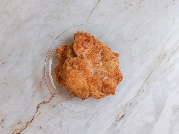 filés de frango frito escorrendo depois de sair da frigideira.