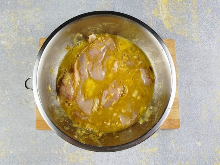 Uma tigela com o frango temperado e ovos batidos.