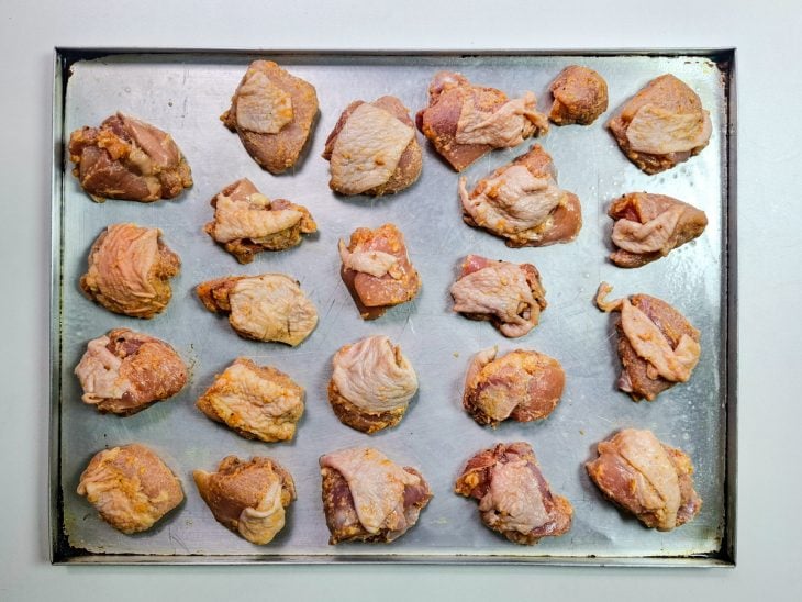 pedaços de frango a passarinho em tabuleiro para assar.