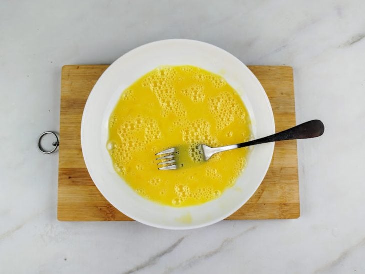 Um prato com ovo batido com garfo.