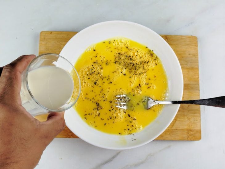 Um prato com ovo batido, leite e temperos.