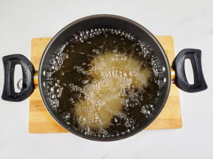 Uma panela com óleo e o frango a fritar.