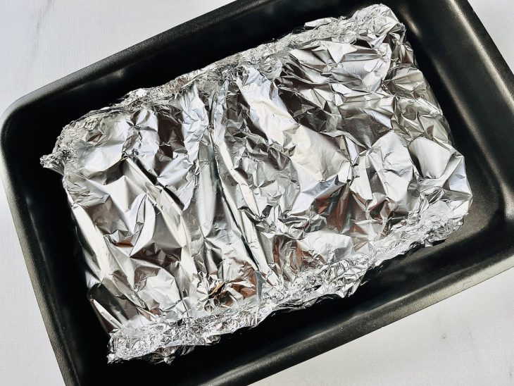 Frango à rolê coberto com papel alumínio.