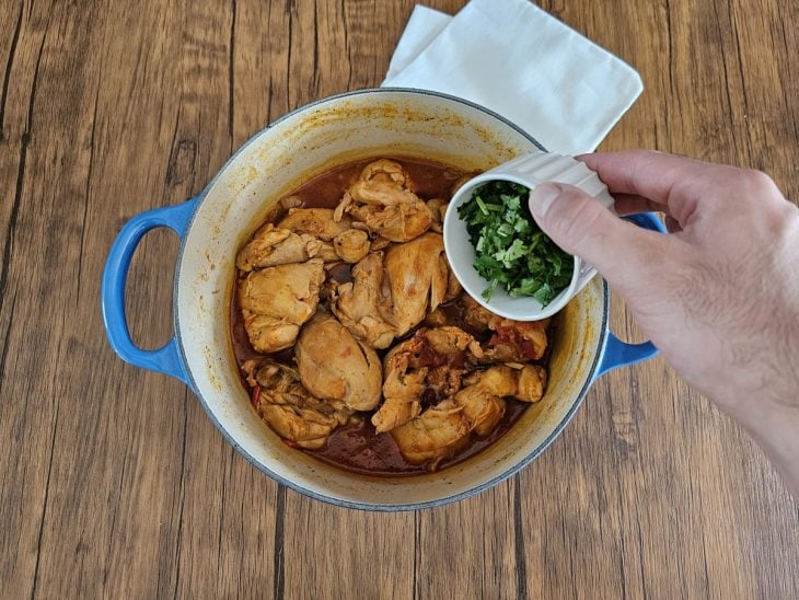 Cheiro-verde sendo adicionado à panela com frango ao molho.