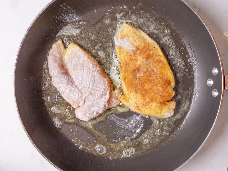 Filés de frango grelhando em uma frigideira.