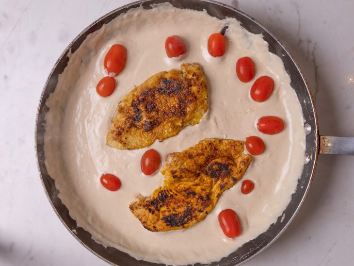 Frango e tomates cereja adicionados a frigideira.