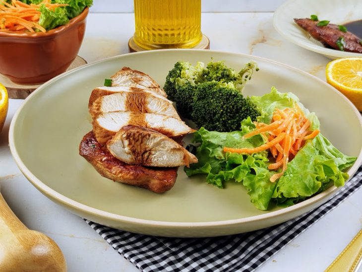 filé de frango com molho de laranja e shoyu finalizado e servido com salada.
