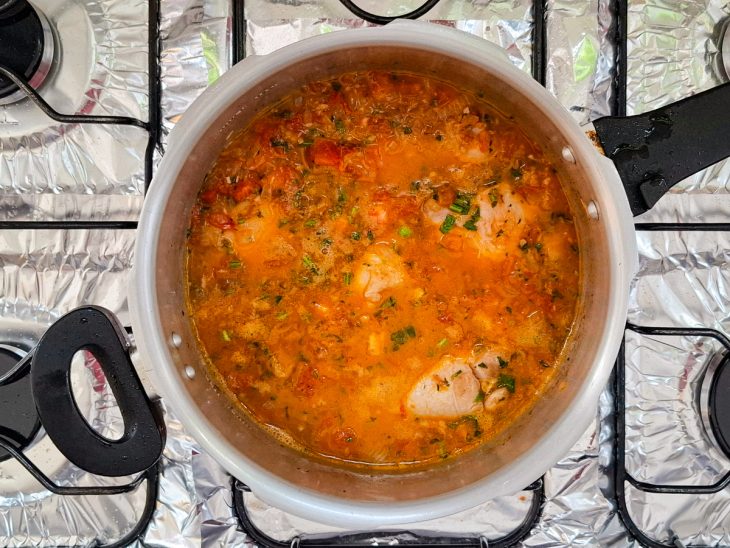 adição de água e temperos para cozinhar frango na pressão.