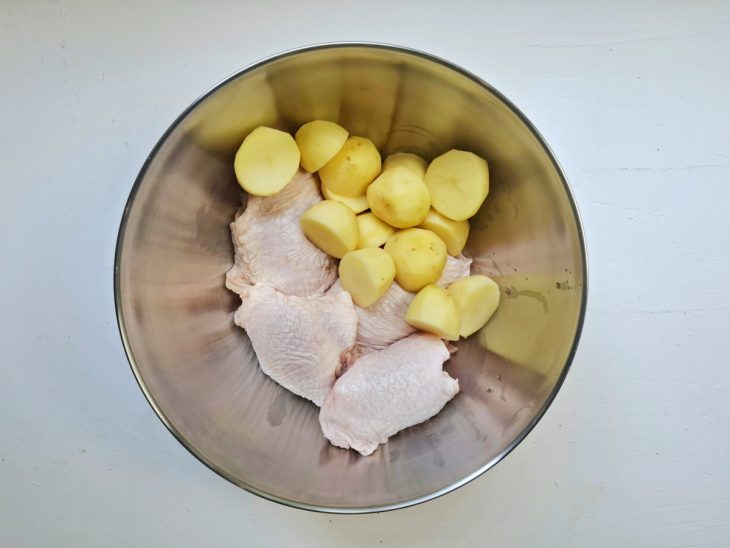 Tigela com pedaços de frango e batatas.