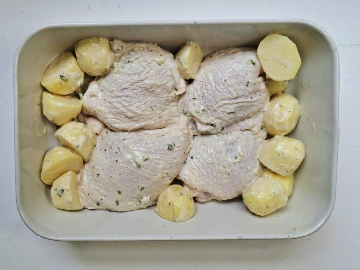 Um refratário com o frango e as batatas prontos para assar.