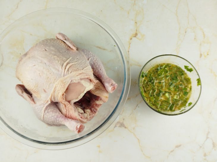 Frango com a pele solta e a marinada ao lado.