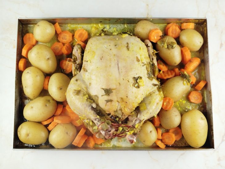 Batatas e cenouras distribuídas na forma com o frango.