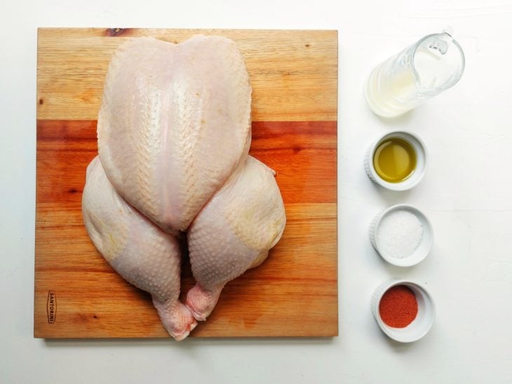 Tábua com frango e temperos sobre uma bancada.