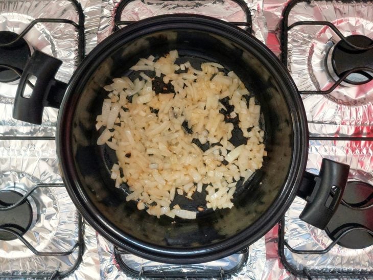 Uma frigideira com manteiga, alho e cebola a dourar.