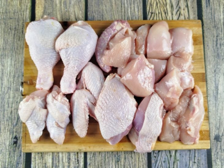 Frango em pedaços sobre uma tábua.