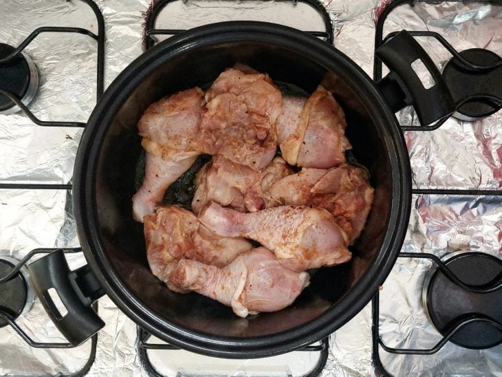 Pedaços de frango colocados com a pele para baixo em uma panela.