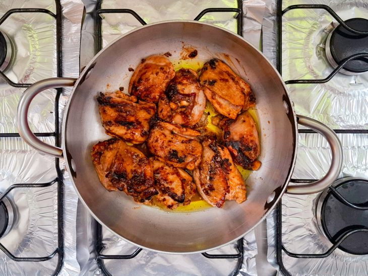 Na panela, os pedaços de frango dispostos e dourados.