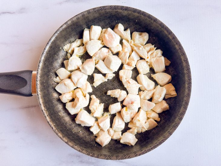 Numa frigideira, os cubos de frango refogados.