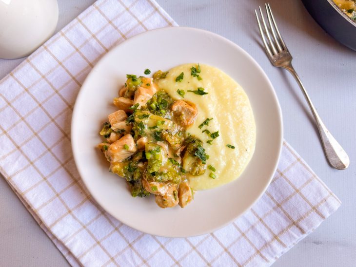 Frango cremoso pronto, servido em prato acompanhado de creme de milho.